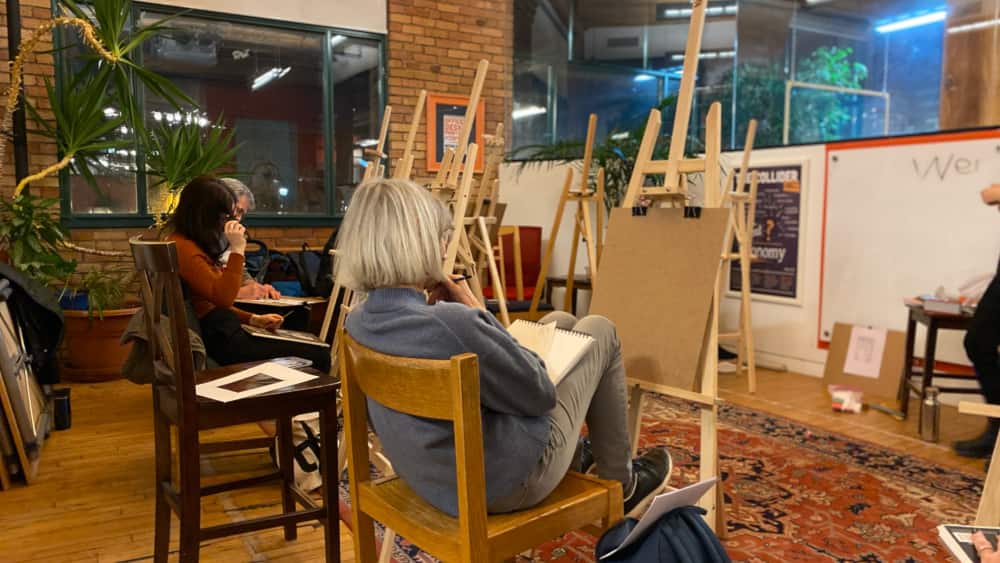 Adult students focused on drawing in a beginner's art class with easels