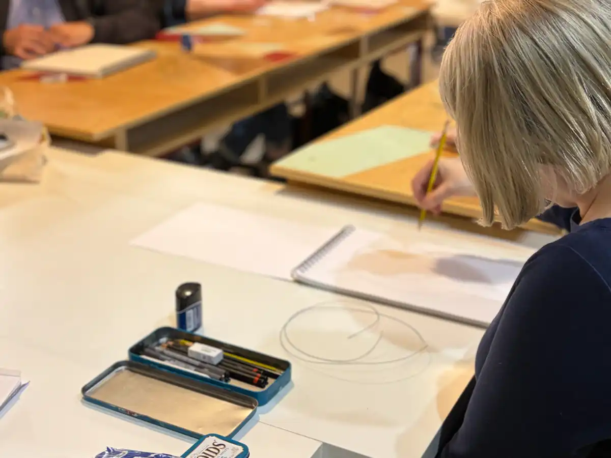 A student sketches with a graphite pencil in a white spiral sketchbook next to a blue metal tin containing drawing pencils Drawing for Beginners at Avenue Road Arts School — Winter 2026