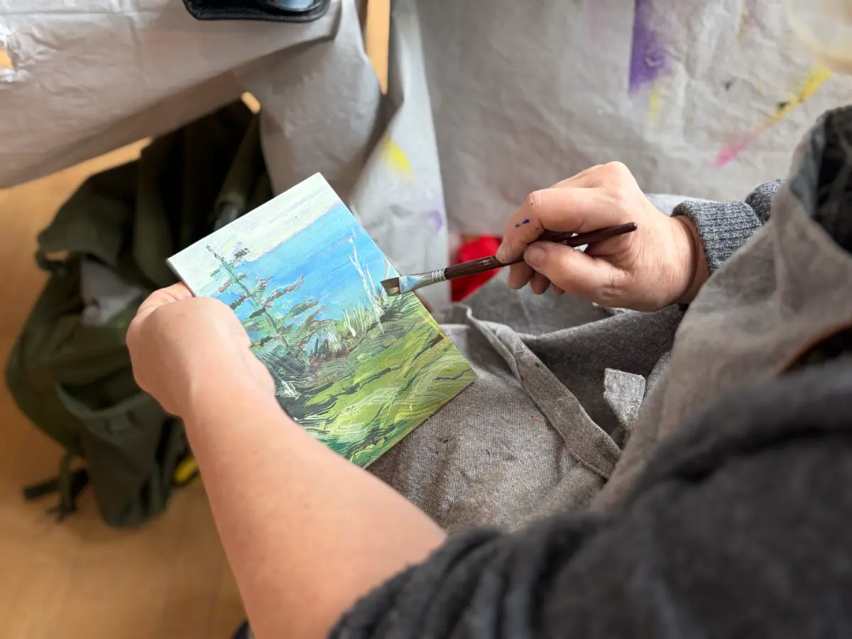 Hands applying gouache paint with a brush to a small landscape painting on a board Gouache Immersion at Avenue Road Arts School — Winter 2026