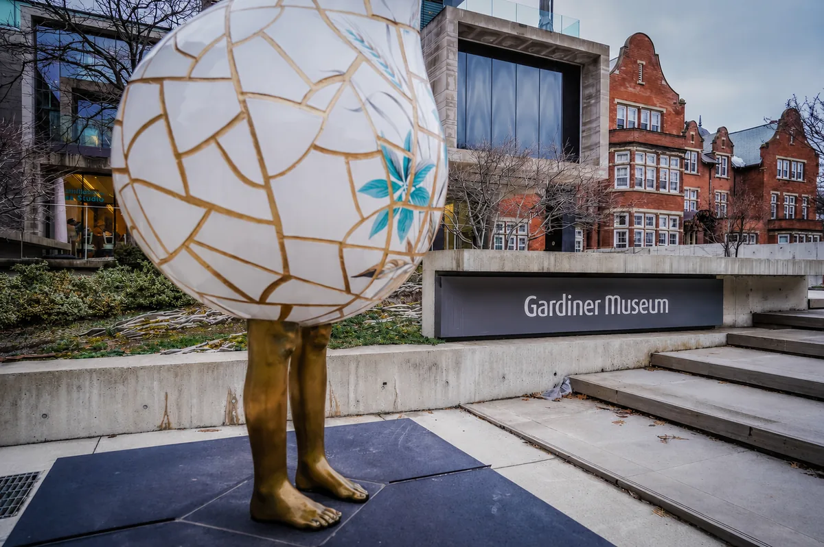 aras-summer-gardiner-museum-2026 Bronze sculpture with a decorative ceramic globe for a head standing outside the Gardiner Museum entrance — Avenue Road Arts School Floral Motif at the ROM course