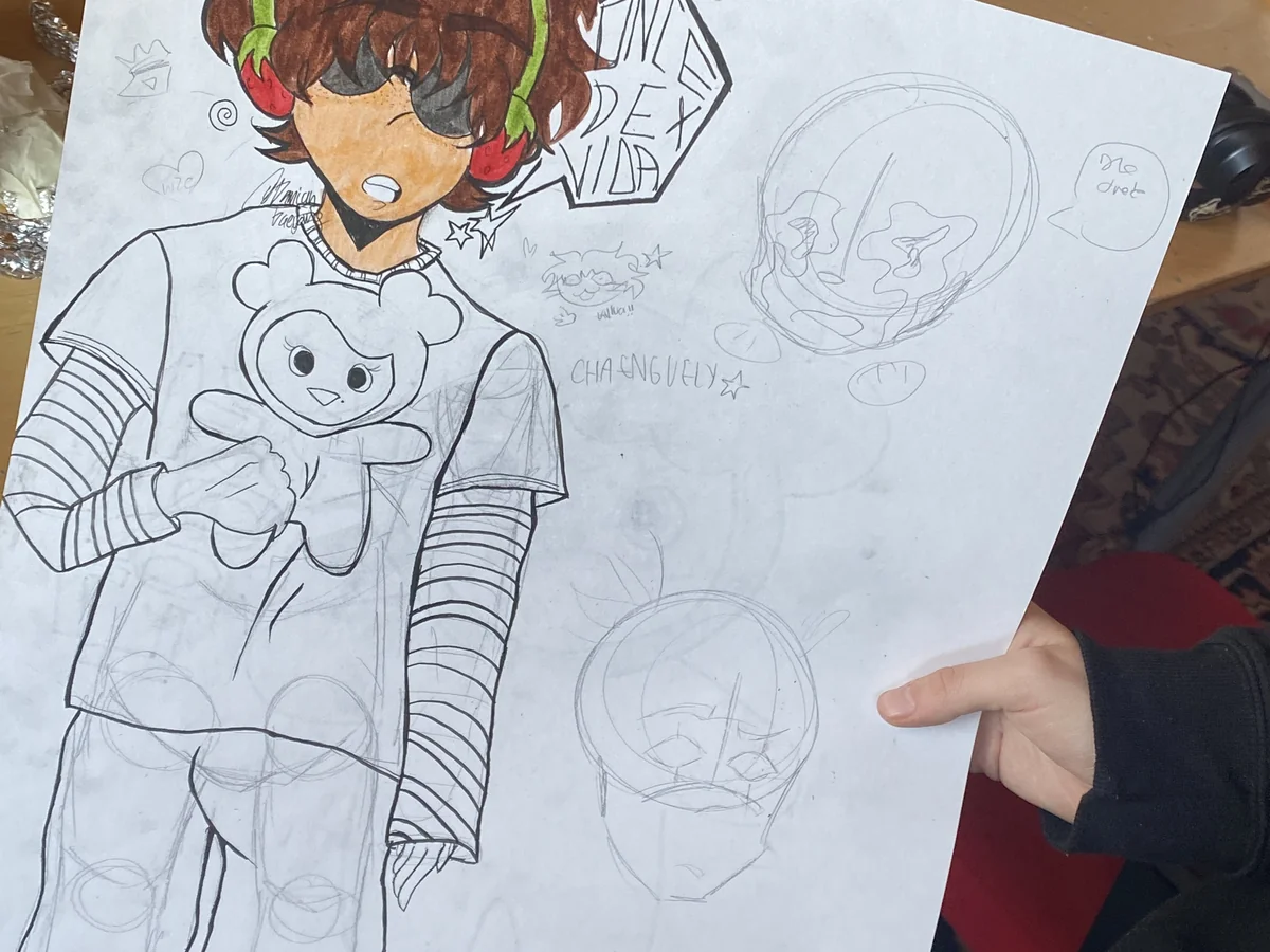 Hand holding a sketchbook page filled with manga-style character drawings in pencil and marker